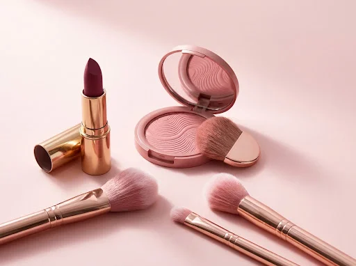 Rose-toned makeup and brushes in soft studio light